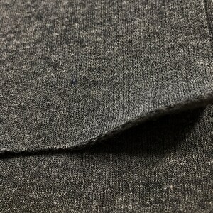 May include: Close-up of a gray knit fabric with a visible seam. The fabric has a soft, textured appearance.