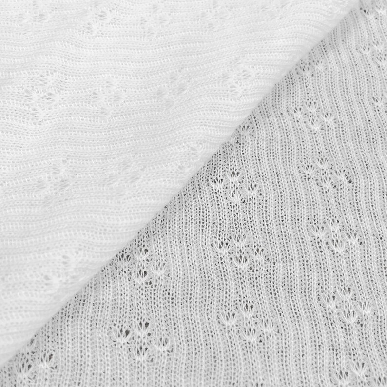 May include: Close-up of two white knitted fabrics with different patterns. The top fabric has a simple, straight pattern, while the bottom fabric has a more intricate, diamond-shaped pattern.