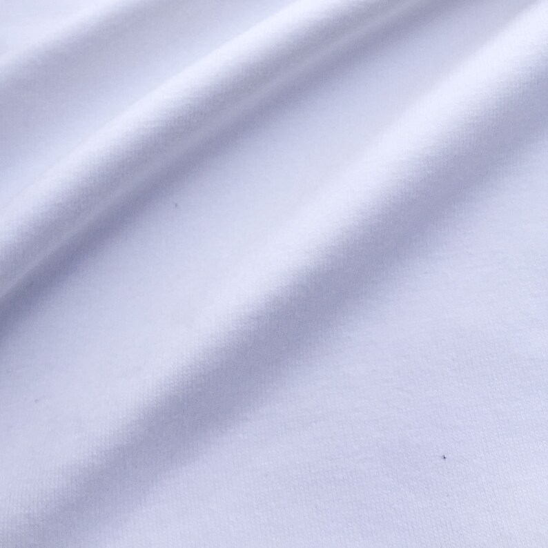 May include: White fabric with a smooth texture and a slight sheen. The fabric is folded and draped, creating soft folds and curves.