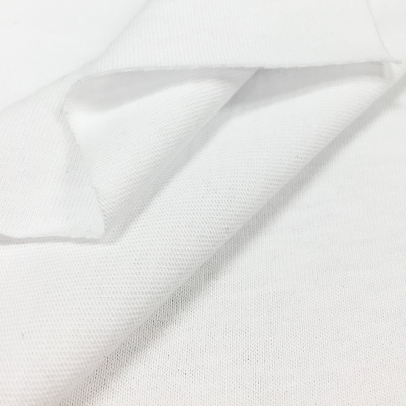 K&ouml;nnte beinhalten: Wei&szlig;er Baumwollstoff mit einer strukturierten Webart. Der Stoff ist in der Mitte gefaltet und zeigt die Innenseite und Au&szlig;enseite des Materials.