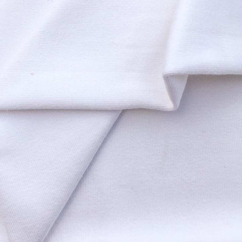 May include: White fabric folded in half, showing the texture of the material.