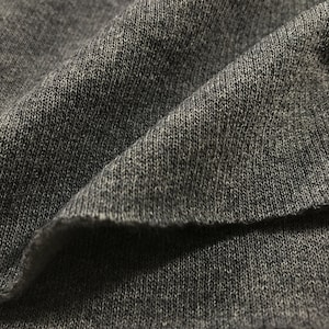 May include: Close-up of a dark gray knitted fabric with a textured surface.