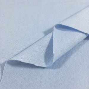 May include: A close-up of a light blue fabric with a textured surface. The fabric is folded in half, showing the inside of the fabric.