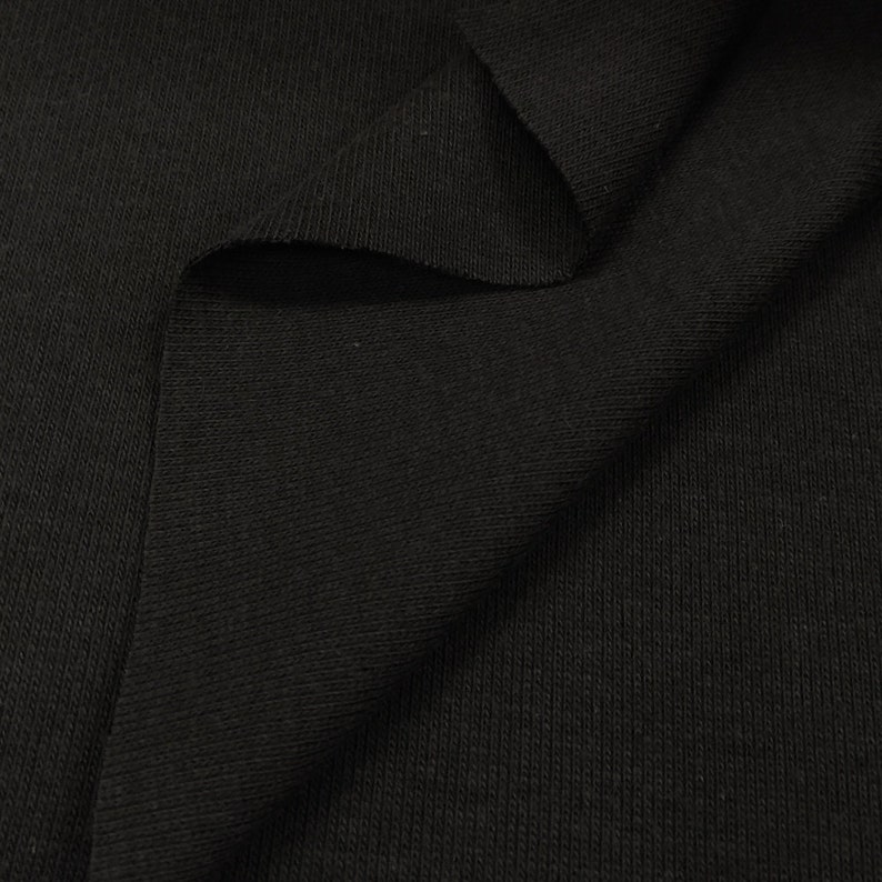 May include: Close-up of black ribbed fabric. The fabric has a soft, textured surface.