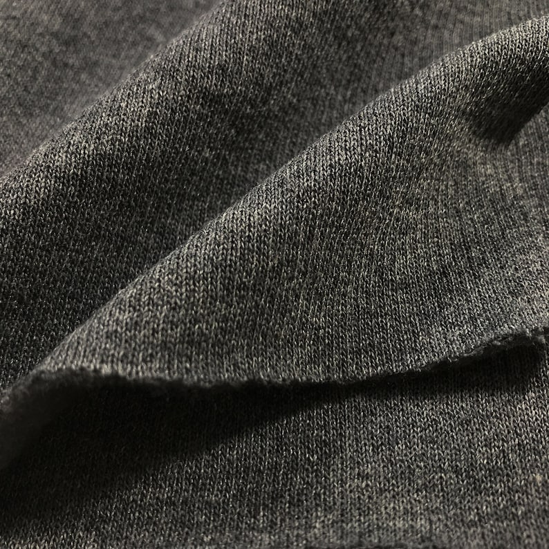 May include: Close-up of a dark gray knitted fabric with a textured surface.
