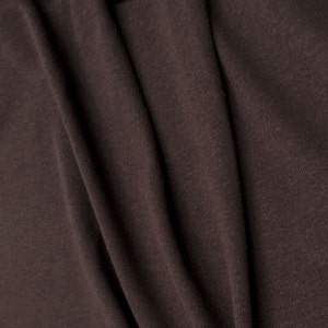 May include: Close-up of a brown fabric with a textured surface. The fabric is folded and has a soft, smooth feel.