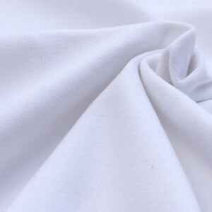 May include: White fabric with a smooth, soft texture. The fabric is folded and draped, creating a soft, flowing look.