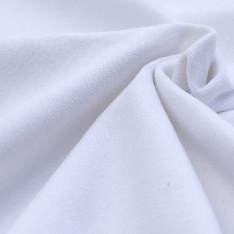 May include: White fabric with a smooth, soft texture. The fabric is folded and draped, creating a soft, flowing look.