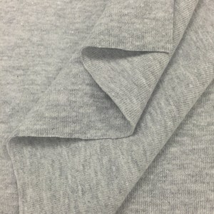 May include: Close-up of a gray, textured fabric with a ribbed pattern. The fabric is folded in a way that shows the texture and the weave.