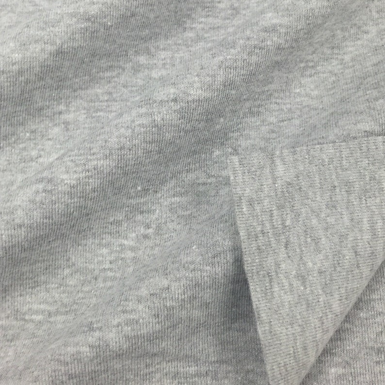 May include: Close-up of a gray, textured fabric with a subtle ribbed pattern. The fabric is folded over, showing the inside of the material.