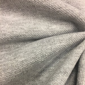 Puede incluir: Primer plano de una tela gris texturizada con un aspecto suave y peludo.