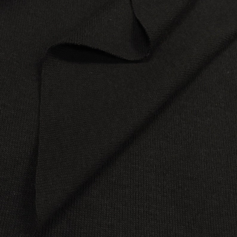 May include: Black ribbed knit fabric. The fabric is folded in half, showing the texture of the knit.