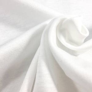 May include: White fabric with a smooth texture, folded and draped in a soft, flowing manner.