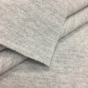Puede incluir: Primer plano de una tela gris texturizada. La tela est&aacute; doblada por la mitad, mostrando la textura suave y peluda.