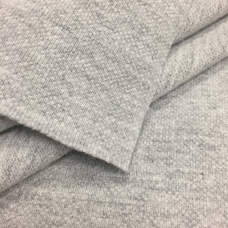 Puede incluir: Primer plano de una tela gris texturizada. La tela est&aacute; doblada por la mitad, mostrando la textura suave y peluda.