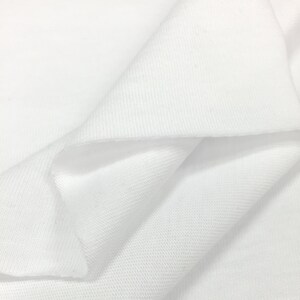 K&ouml;nnte beinhalten: Wei&szlig;er Stoff mit einer glatten, strukturierten Oberfl&auml;che. Der Stoff ist so gefaltet, dass die Textur und der Fall sichtbar werden.