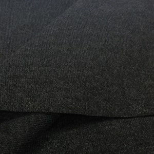 Puede incluir: Primer plano de una tela gris oscuro con una superficie texturizada y acanalada. La tela est&aacute; doblada, mostrando el interior del material.
