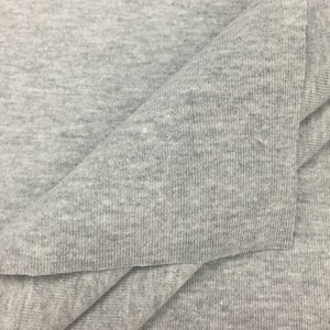 May include: Close-up of a gray, textured fabric. The fabric is folded in half, showing the inside and outside of the material.