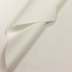 May include: A close-up of a white fabric with a smooth texture. The fabric is folded in half, creating a soft, gentle curve.
