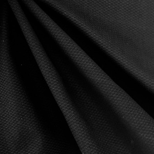 May include: Black textured fabric with a subtle waffle weave pattern. The fabric is folded and draped, showcasing its texture and drape.