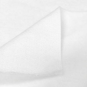 May include: Close-up of a white fabric with a textured surface. The fabric is folded in half, showing the inside and outside of the material.