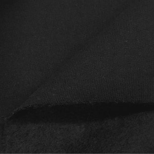 Pu&ograve; includere: Primo piano di un tessuto nero con una texture morbida e soffice. Il tessuto ha una superficie liscia e uniforme con un leggero bagliore.