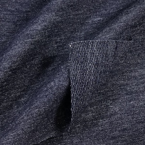 May include: Close-up of a dark blue fabric with a textured surface. The fabric is folded over, revealing the inside of the fabric, which is a lighter shade of blue.