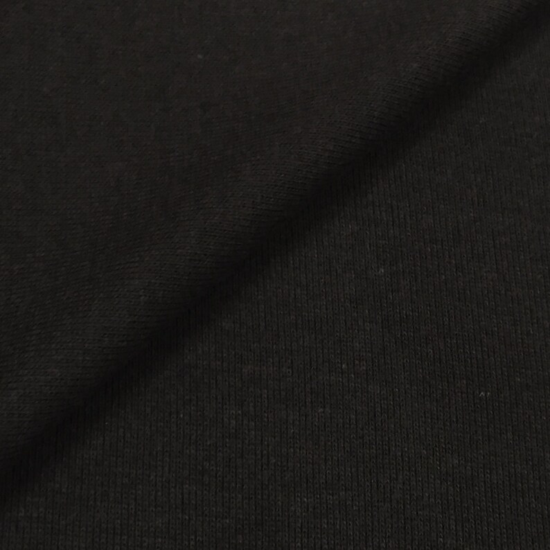 May include: Black ribbed fabric with a smooth texture. The fabric is folded in half, showing the inside and outside of the material.