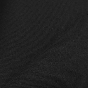 Pu&ograve; includere: Tessuto nero con una texture liscia e uniforme. Il tessuto ha una leggera lucentezza ed &egrave; privo di pieghe.