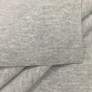 May include: Close-up of a gray, textured fabric. The fabric is folded in half, showing the inside and outside of the material.