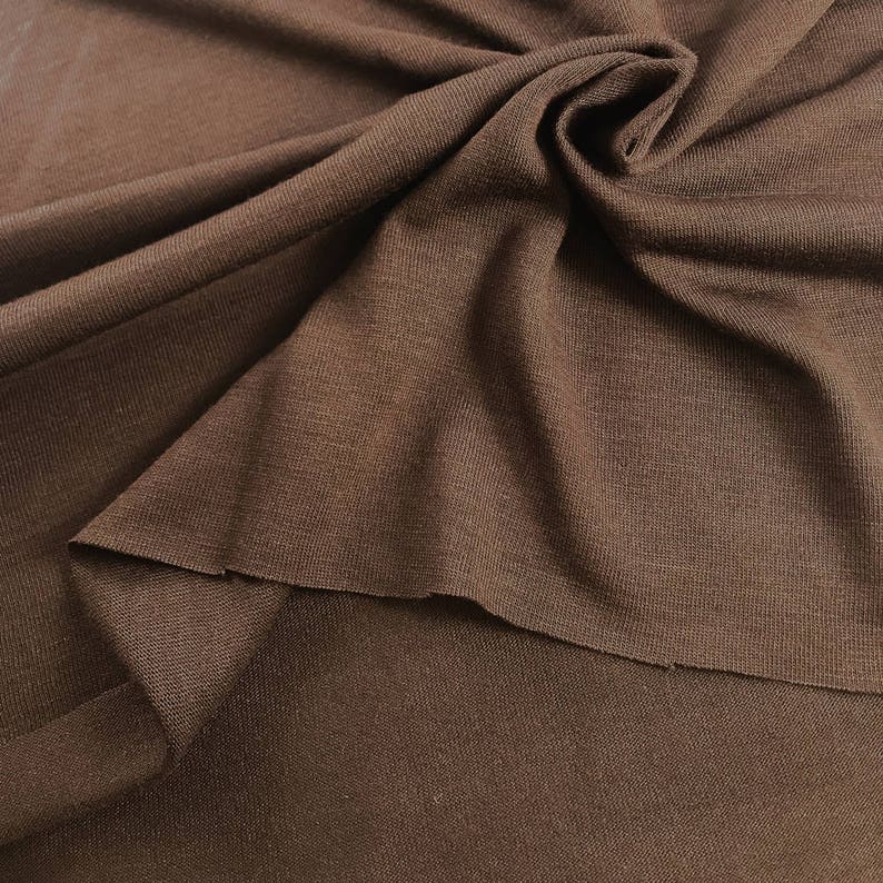 May include: A close-up of a brown ribbed knit fabric. The fabric is soft and has a subtle texture.