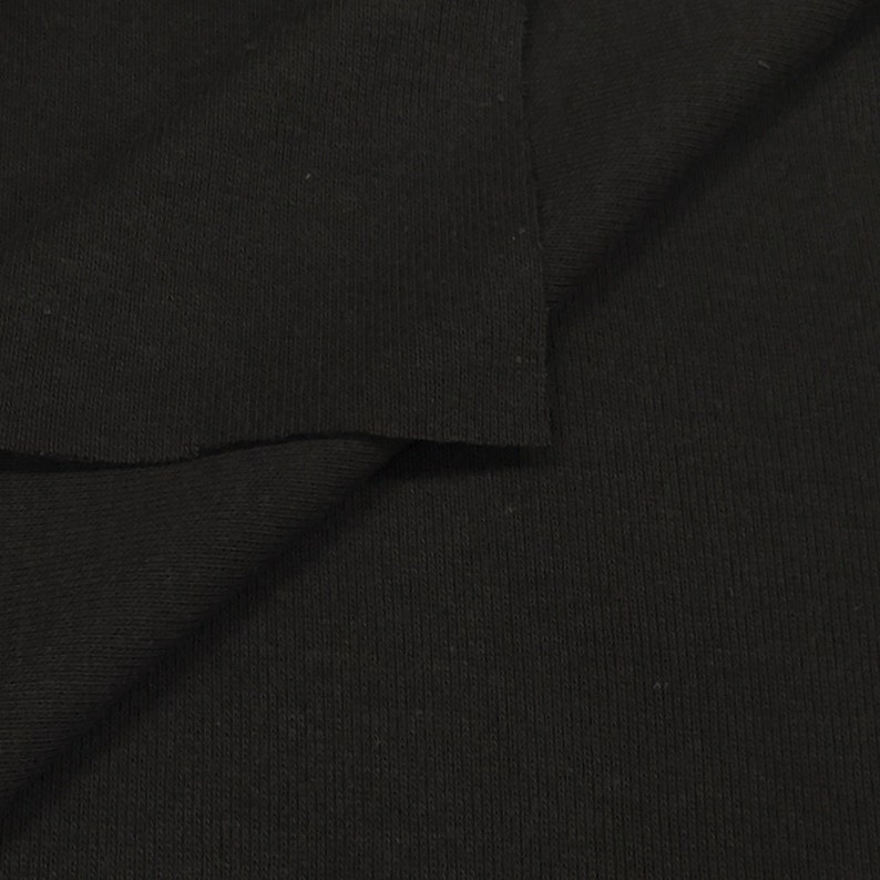 May include: Black ribbed knit fabric. The fabric is folded in half, showing the texture of the knit.