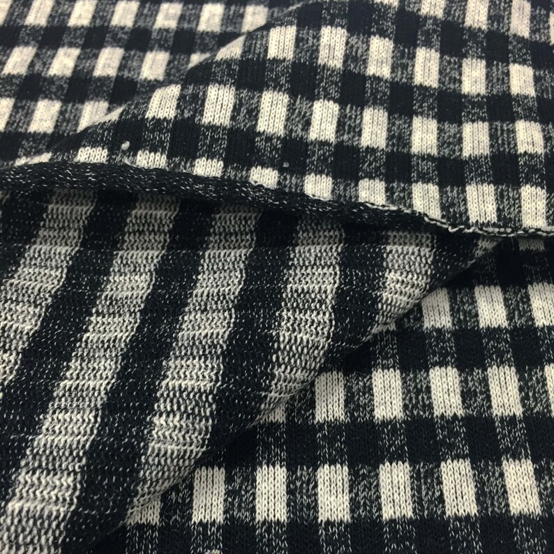 May include: Black and white gingham knit fabric with a striped pattern. The fabric is soft and has a textured surface.