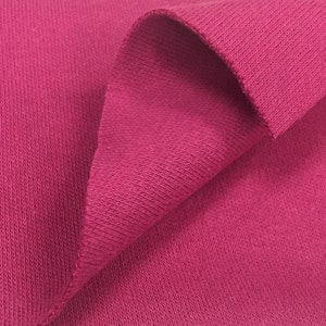 May include: Close-up of a folded piece of pink fabric with a textured surface.