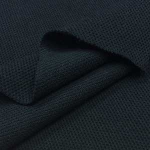 May include: Close-up of a dark blue knit fabric with a textured waffle pattern. The fabric is folded in a way that shows the texture and the color.