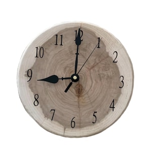 May include: A round wooden clock with black hands and black numbers on a white background. The clock is made from a tree trunk slice and has a natural wood grain pattern.