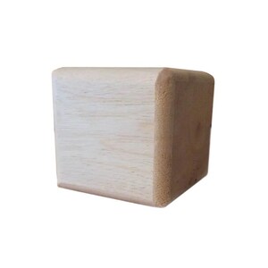 May include: A light wood corner block with a rounded edge. The block is made of unfinished wood and has a natural wood grain.