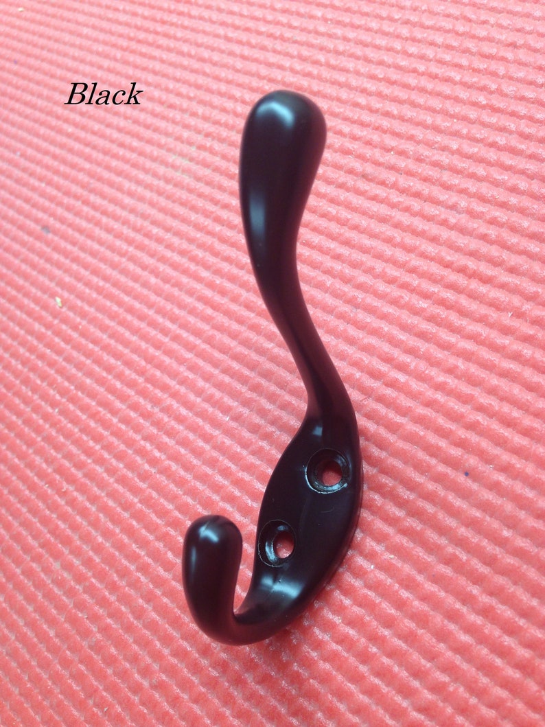 Puede incluir: Gancho de metal negro con un dise&ntilde;o de gancho doble. El gancho est&aacute; sobre un fondo rojo.