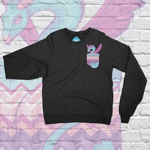 Puede incluir: Sudadera negra con un dragón colorido en el bolsillo. El dragón es rosa, morado y azul sobre un fondo azul claro.