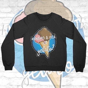 Könnte beinhalten: Schwarzes Sweatshirt mit einem Aufdruck eines rosa und braunen Eisbechers auf blauem Hintergrund. Der Text auf dem Aufdruck lautet "Andiamo a pigia er gelato?"