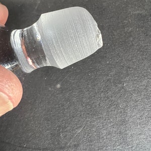 May include: Clear glass bottle stopper with a frosted top. The stopper has a slightly chipped edge.