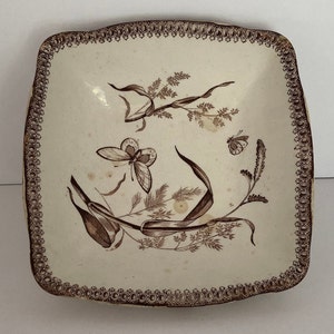 May include: A square, white ceramic dish with a brown border and a brown floral design featuring butterflies.