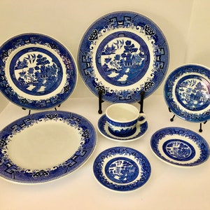 May include: A set of blue and white willow pattern china, including a teacup and saucer, a dinner plate, a salad plate, and two smaller plates.