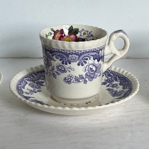 May include: Three antique teacups and saucers. The teacups feature floral and botanical designs in various colors, including red, blue, and yellow. The saucers have coordinating patterns. The teacups are made of porcelain.