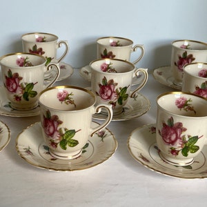 May include: Set of ten vintage teacups and saucers with a floral pattern. The cups and saucers are white with a gold trim and feature pink roses with green leaves.