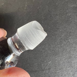 May include: Close-up of a clear glass bottle stopper with a textured surface.
