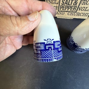 Peut inclure: Sali&egrave;re et poivri&egrave;re en c&eacute;ramique blanche avec un motif d&eacute;coratif bleu et blanc. Les sali&egrave;res et poivri&egrave;res ont un dessus arrondi et un motif d&eacute;taill&eacute; autour de la base. L'emballage en arri&egrave;re-plan indique "Churchill of England Salt & Pepper".