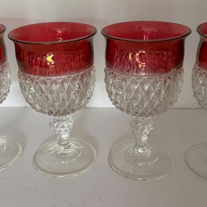 May include: Set of four clear glass wine goblets with a diamond pattern and a red ruby colored rim.
