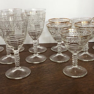 May include: Set of 13 clear glass wine glasses with gold trim. The glasses have a fluted design and a stemmed base.