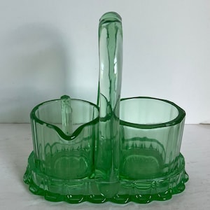 May include: Green glass sugar and creamer set with a handle. The set has a scalloped edge and a ribbed design.